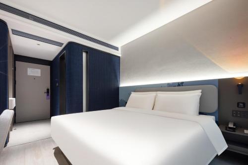 深圳深圳南山来福士广场轻居酒店的卧室配有白色的床和蓝色的墙壁