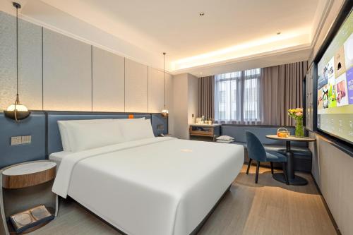 上海上海外滩南京东路步行街亚朵X酒店的一间酒店客房,配有一张白色的床和一张书桌