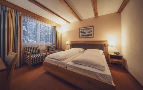 达沃斯Mountain Plaza Hotel的卧室配有床、椅子和窗户。