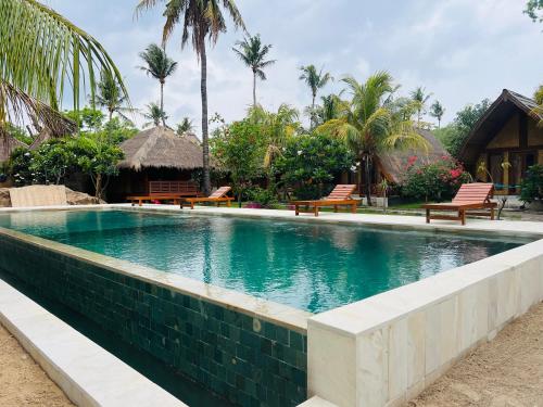 吉利阿尔吉塔吉利简易别墅酒店的一个带长椅和棕榈树的度假村内的游泳池