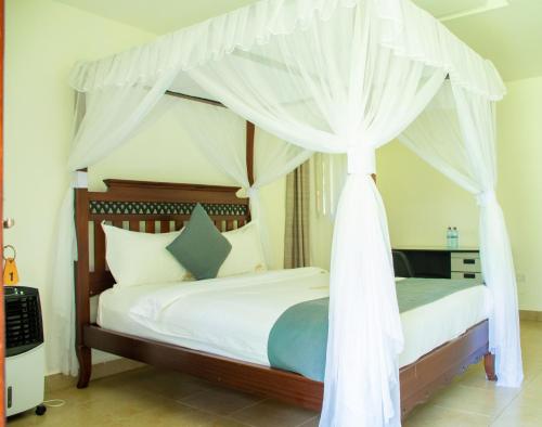 基苏木Harry's Kisumu Oasis的卧室配有带白色窗帘的天蓬床