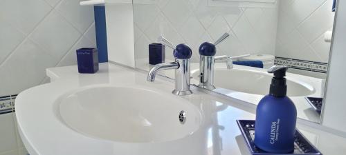 OrdonnacCoquet studio en Médoc, Jacuzzi et climatisation的白色浴室水槽和蓝色瓶子