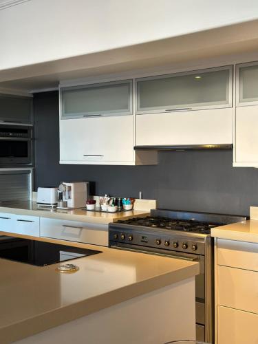 开普敦The Atlantic DonReal Guesthouse的厨房配有白色橱柜和炉灶烤箱。