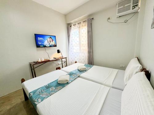 宿务Gplace Hotel的配有电视的客房内的两张床