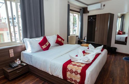 加德满都Kusum Airport Hotel的一间卧室配有一张带红色和白色枕头的大床