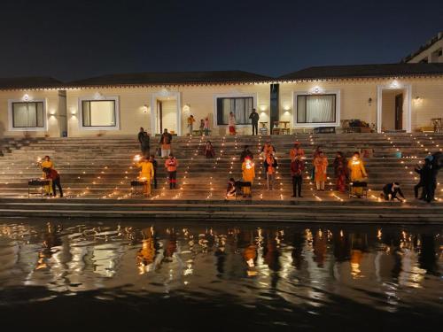 AyodhyaAyodhya haat Luxury Cottages的一群人晚上站在水边的台阶上
