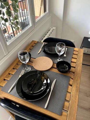 让蒂伊Studio cozy proche Paris的一张木桌,上面放有盘子和酒杯