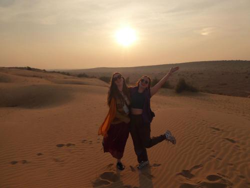 斋沙默尔Martine guest house的日落时分在沙漠中行走的两名女孩