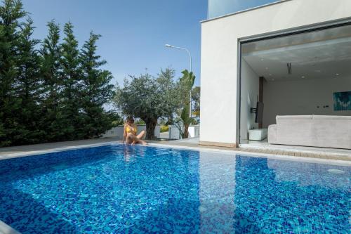 普罗塔拉斯Sunrise Seaview Villas的坐在蓝色游泳池边的女人