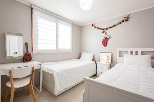 高阳市Ria House的一间卧室配有两张床、一张桌子和吉他。