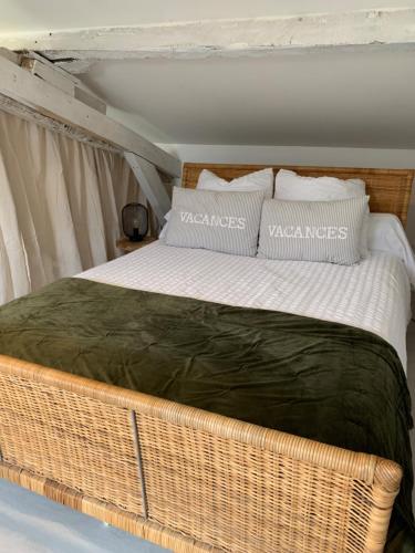 特雷利萨克Maison de famille 24的一张大柳条床,上面有枕头