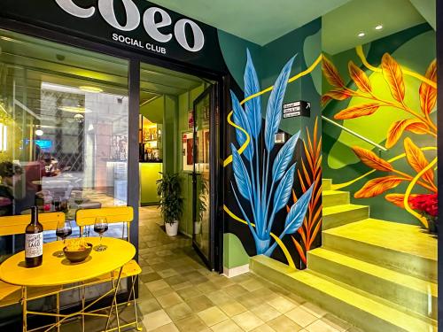 马拉加COEO Pod Hostel - Part of COEO Experience的餐厅设有黄色桌子和彩色壁画