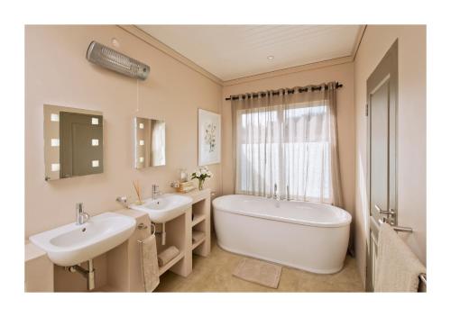 Van ReenenOaklands Farm Stay的一间带两个盥洗盆、浴缸和窗户的浴室