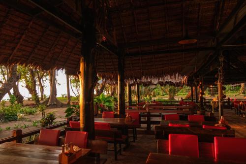 俊穆岛JOY简易别墅度假村&餐厅的餐厅设有木桌和红色椅子