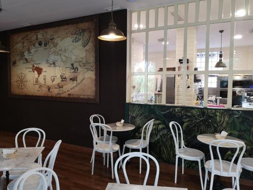 平托El Indio CHocolatería Boutique Hostel的餐厅设有白色的桌椅,墙上挂有绘画作品