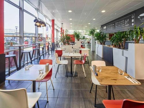 鲁瓦西昂法兰西宜必思巴黎戴高乐机场酒店的餐厅设有桌椅和窗户。
