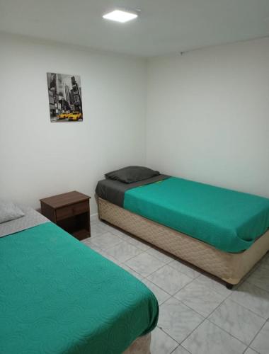 卡尔德拉Hospedaje GYT Caldera的配有绿床单的客房内的两张床