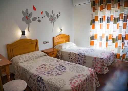 巴萨HOSTAL CACHE的酒店客房,设有两张床,墙上挂着鲜花。