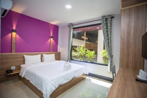 Amnat CharoenOYO 75464 Nakarin Hotel的一间卧室配有一张床和紫色的墙壁