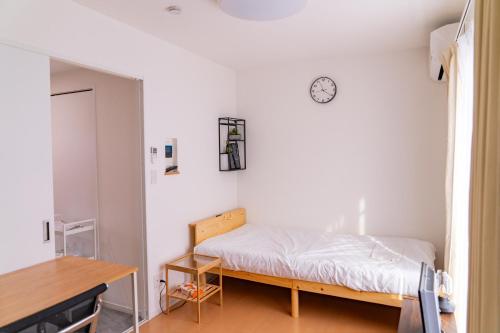 东京One Point Five的卧室配有一张床,墙上挂着一个钟