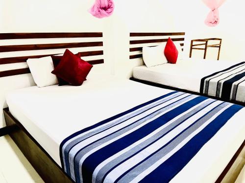 波隆纳鲁沃Geethani Tourists Home的两张床铺,房间配有红色和蓝色枕头