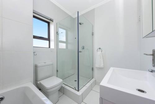 SandtonCaptivating 2-Bed Apartment in Sandton的白色的浴室设有卫生间和玻璃淋浴间。