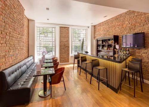 伦敦凯撒酒店的一间酒吧,配有沙发和椅子,并拥有砖墙