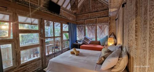 吉利特拉旺安Villas Light House - Eco-Traditional Joglo的一间设有床铺的卧室,位于带窗户的房间内