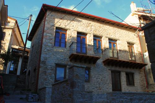 阿拉霍瓦Δρυάδες Suites的石头房子设有红色窗户和阳台