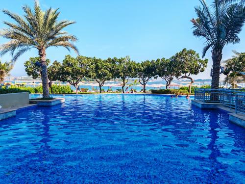 迪拜Seaside Serenity Residence Elegant 1BR Escape in Palm Jumeirah by La Buena vida holiday homes的度假村内棕榈树游泳池
