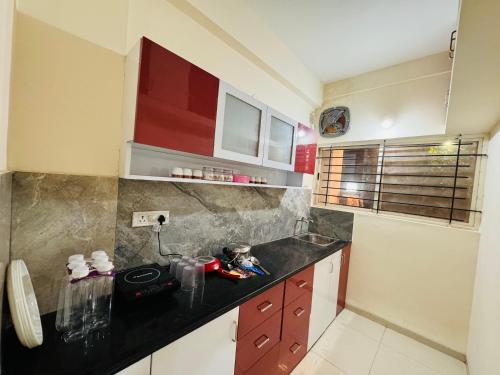 印多尔Home Escape 1BHK Apartment Near Bombay Hospital的厨房配有红色橱柜和黑色台面