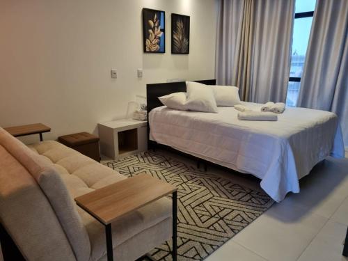 波梅罗迪Flat Home Business Centro de Pomerode的一间卧室配有一张床、一张沙发和一张桌子