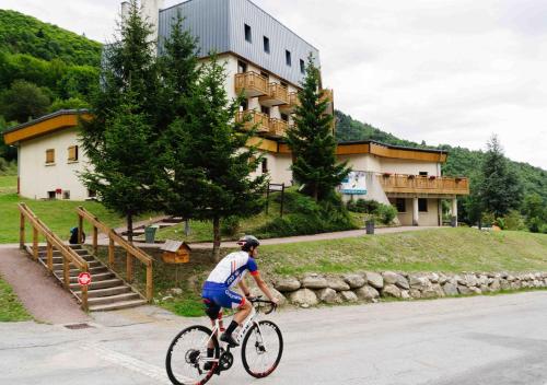 圣费朗索瓦-隆尚Résidence Routes du Monde ATC Saint-François-Longchamp的一个人在建筑物前骑着自行车