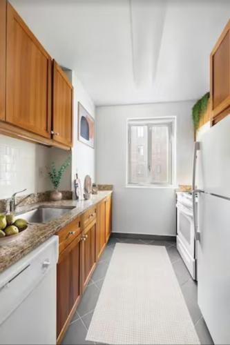 纽约Two bedroom condo in Upper West Side的厨房配有木制橱柜和白色冰箱。