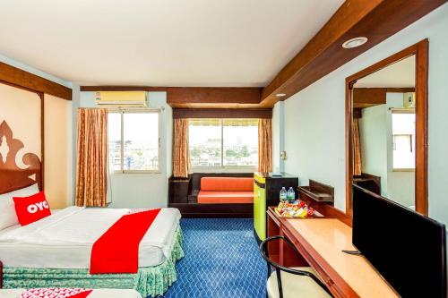 素叻OYO 441 Grand Thara Hotel的酒店客房配有一张床、一张书桌和一台电视。
