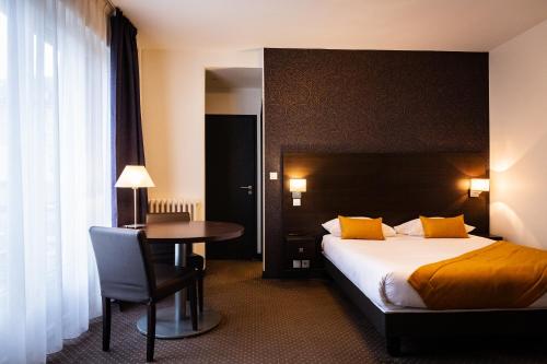 凯恩Hotel Astrid Caen centre的酒店客房配有一张床铺和一张桌子。