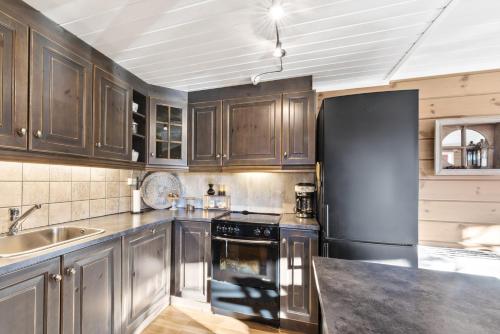 史特林Hytte Stryn skisenter的厨房配有木制橱柜和黑色冰箱。