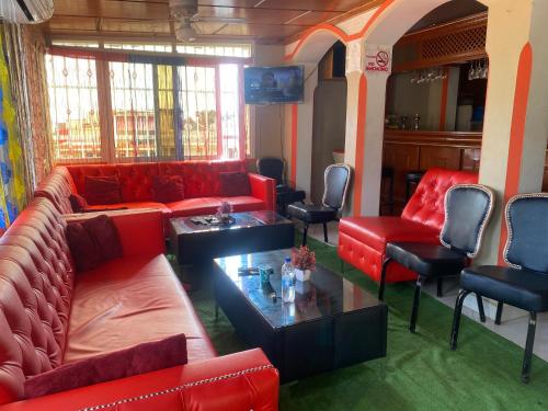 海地角Clientèle Hotel的客厅配有红色的沙发和椅子