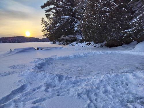 Algonquin HighlandsThe Bear Cave Cottage at Little Kennisis Lake的一堆雪,太阳在背后