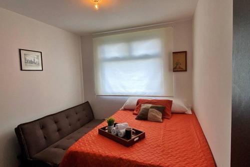 危地马拉Apartamento en centro Ciudad de Guatemala z12的一间卧室配有一张带橙色毯子和窗户的床。