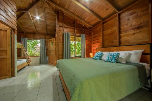 福尔图纳Eden Organic Farm & Bungalows的卧室配有一张床铺,位于带木墙的房间内