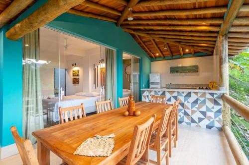 伊利亚贝拉Casa Bambolê em Ilhabela的一间带木桌的用餐室和一间厨房