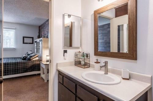 马姆莫斯湖Cozy Cabin-Style Condo in Central Location的一间带水槽和镜子的浴室以及一张床
