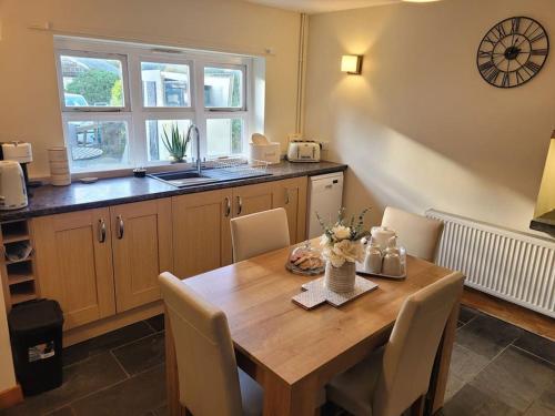 LlwyngwrilCosy modern cottage by the sea, heart of snowdonia的厨房配有木桌、椅子和水槽