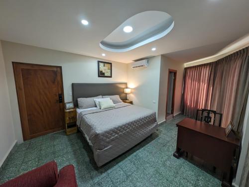 圣萨尔瓦多Hotel Abrego的一间卧室配有一张床、一张桌子和一张四柱床。