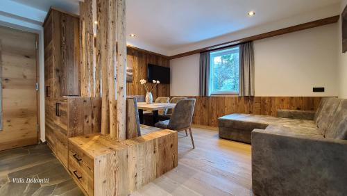 奥蒂塞伊Villa Dolomiti的客厅设有木墙和桌椅