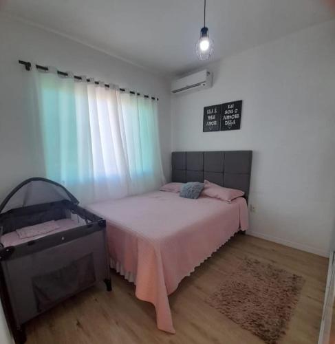 南圣弗朗西斯科Apartamento na praia de Ubatuba, São Francisco do sul的一间卧室配有一张带粉色毯子的床和窗户。