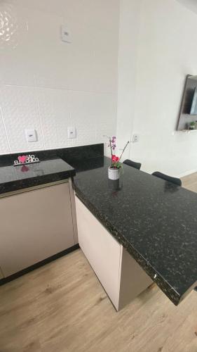 南圣弗朗西斯科Apartamento na praia de Ubatuba, São Francisco do sul的厨房配有黑色的台面和花瓶