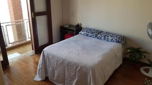 圣保罗Suíte em São Paulo的一间卧室配有一张带白色毯子的床和窗户。