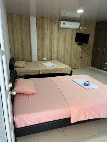 IníridaPosada Turística Marova的配有粉红色床单的客房内的两张床